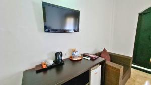 a room with a table with a tv on the wall at Satriya Cottages in Kuta