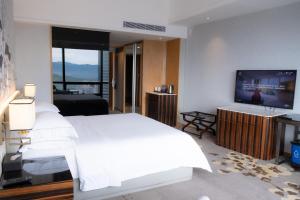 a bedroom with a white bed and a flat screen tv at Huaqiang Plaza Hotel Shenzhen, Enjoy Complimentary Mini Bar & Night Snack, Add breakfast - enjoy complimentary afternoon tea in Shenzhen