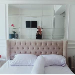 une femme debout devant un miroir derrière un lit dans l'établissement Apartement Podomoro golf view exit toll cimanggis, à Bogor