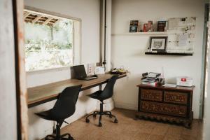 um escritório com uma secretária com 2 cadeiras e um computador portátil em East room at Semadi Living em Darmasaba