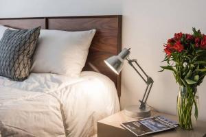 a bed with a table with a lamp and a vase of flowers at Condesa Residence Amsterdam E Cozy Living Space in the Heart of the City on Amsterdam Avenue in Mexico City