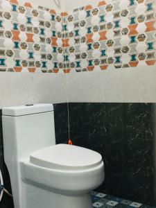 ein weißes WC im Bad mit einer Kachelwand in der Unterkunft Rajas Basera Homestay in Alappuzha