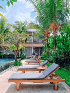 a row of chaise lounges by the pool at a resort at Kahayana Suites Ubud in Ubud