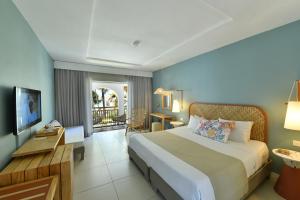 um quarto de hotel com uma cama grande e uma varanda em Veranda Palmar Beach Hotel & Spa - All Inclusive em Belle Mare