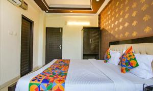 a bedroom with a large bed with colorful sheets and pillows at FabHotel CP Palace Race Course in Dehradun