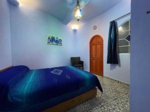 um quarto com uma cama azul e uma cadeira em Dar Fatima em Chefchaouen