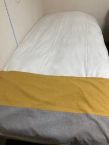 a bed with a yellow and white blanket on it at GreenHotel in Tokyo