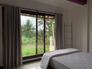 a bedroom with a bed and a large window at Large House with Swimming Pool-Griya Alcheringa in Bedoyo