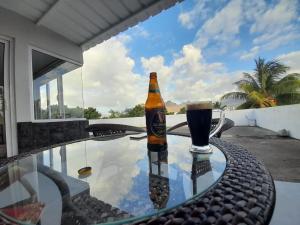 a bottle of beer on a glass table with a drink at Rooftop apartment in Port Louis