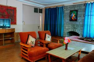 uma sala de estar com cadeiras laranja e uma lareira em Manu Villa - 1,2,3 Bedroom Personal Luxury Villas Available in Manali em Manali