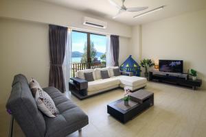 a living room with a couch and a tv at By The Sea Beach Front Apartment in Batu Ferringhi