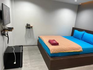 a bedroom with a bed with blue sheets and a television at CK Residence in Songkhla