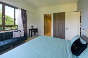 a bedroom with a blue bed and a couch at By The Sea Beach Front Apartment in Batu Ferringhi