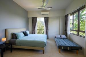 a bedroom with a bed and a bench in front of a window at By The Sea Beach Front Apartment in Batu Ferringhi