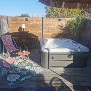 a hot tub on a patio with a chair and a table at Aux Couleurs de la Baie in Cherrueix