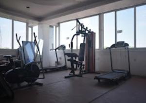 a gym with exercise equipment in a room with windows at Hotel Midway & Zaika Restaurant Bihar in Madhipura