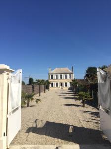 ein weißes Haus mit einem Tor und einer Einfahrt in der Unterkunft La Chartreuse des Vignes in Ludon-Médoc