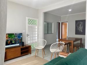 uma sala de estar com um sofá e cadeiras e uma televisão em Linda Casa com Piscina em Marília