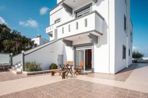 a white house with a patio with a table and chairs at White Pearl Apolakkia 1 in Apolakkiá