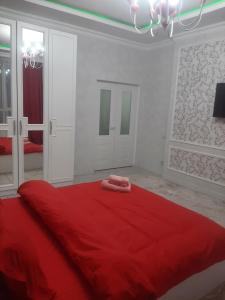 - un lit rouge avec 2 serviettes dans l'établissement Красивая квартира в центре городе Шымкент. ЖК Аль-Фараби, à Chimkent