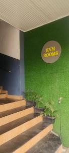 エルナクラムにあるkvm rooms and dormitoryの階段と看板のある緑の壁の建物