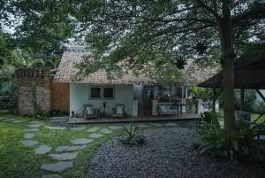 uma pequena casa branca com uma árvore e um quintal em East room at Semadi Living em Darmasaba