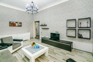 a living room with a couch and a tv at Azneft Square Deluxe Apartment in Baku