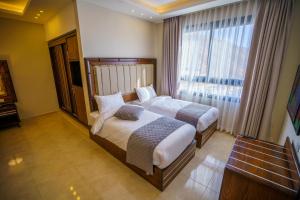 a bedroom with two beds and a large window at Petra Icon Hotel in Wadi Musa