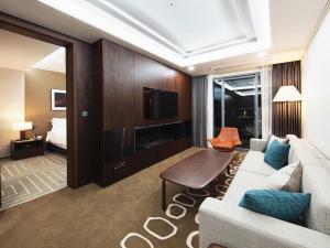 Best Western Plus GyeongJu في جيونجو: غرفة معيشة مع أريكة وتلفزيون وسرير