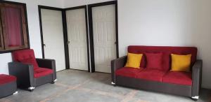 - un salon avec deux chaises et un canapé rouge dans l'établissement Casa Linda, à San Pedro de la Laguna
