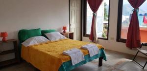 une chambre avec un lit avec une couverture jaune et verte dans l'établissement Casa Linda, à San Pedro de la Laguna