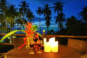 a table with two glasses of wine and candles at Elegant Horizons in Ko Chang