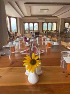 a long wooden table with a vase with a yellow flower at Shomo Chuki Resort in Paro