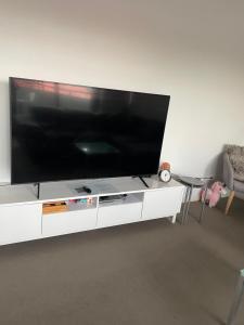una grande TV a schermo piatto su un centro di intrattenimento bianco di Ocean view 2 Bedroom apartment a Sydney