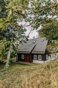 ein kleines schwarzweißes Haus mit einer roten Tür in der Unterkunft Chaloupka Dvě Sestry in Kořenov