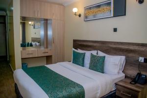 um quarto de hotel com uma cama grande e um telefone em The Kolel Hotel and Suites em Eldoret