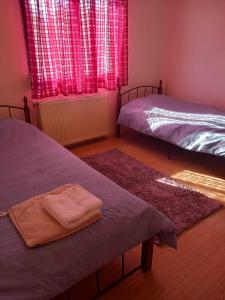 - une chambre avec 2 lits et une fenêtre avec des rideaux rouges dans l'établissement Μονοκατοικια 3 δωματιων, à Kateríni