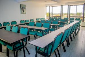 a row of tables and chairs in a room with windows at The Kolel Hotel and Suites in Eldoret