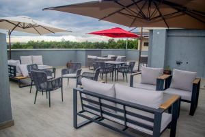 eine Terrasse mit Tischen, Stühlen und Sonnenschirmen in der Unterkunft The Kolel Hotel and Suites in Eldoret