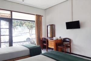 a bedroom with two beds and a desk and a window at Vanda Villa in Batu