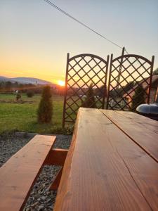 a wooden table with a gate and the sunset in the background at Domki POD STARĄ PODKOWĄ Limanowa Nowy Sącz Kraków in Limanowa