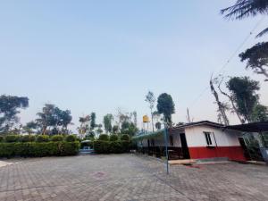 a parking lot with a building and trees in the background at Giri Darshini Homestay - Simple Rooms with Pool & Private Falls in Chikmagalūr