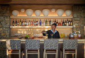 a man standing at a bar with a glass of wine at Kwandwe Ecca Lodge in Grahamstown