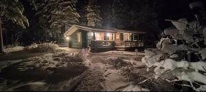 una cabaña de madera en la nieve por la noche en Villa Latvus, en Rovaniemi