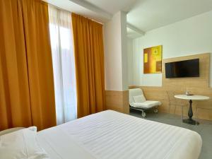 Un dormitorio con una cama y una silla y un televisor. en Navigli Suites, en Milán