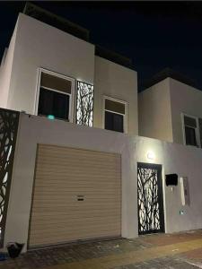 une maison blanche avec une porte de garage devant elle dans l'établissement فيلا كاملة ب 5 غرف نوم عرض خاص للفترات الطويلة و الكاش, à Dammam