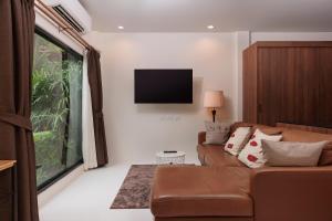ein Wohnzimmer mit einem Sofa und einem Flachbild-TV in der Unterkunft House with pool near the beach - Kamala #05 in Kamala Beach