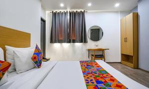 1 dormitorio con 1 cama grande y espejo en FabHotel VT Paschim Vihar en Nueva Delhi