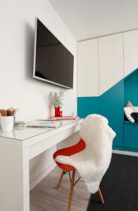 Elle comprend un bureau blanc avec une chaise rouge et une télévision. dans l'établissement Studio Alegre, à Bucarest