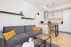 a living room with a gray couch and yellow pillows at Spacious Apartment Aleja Rzeczypospolitej with Balcony by Noclegi Renters in Gdańsk